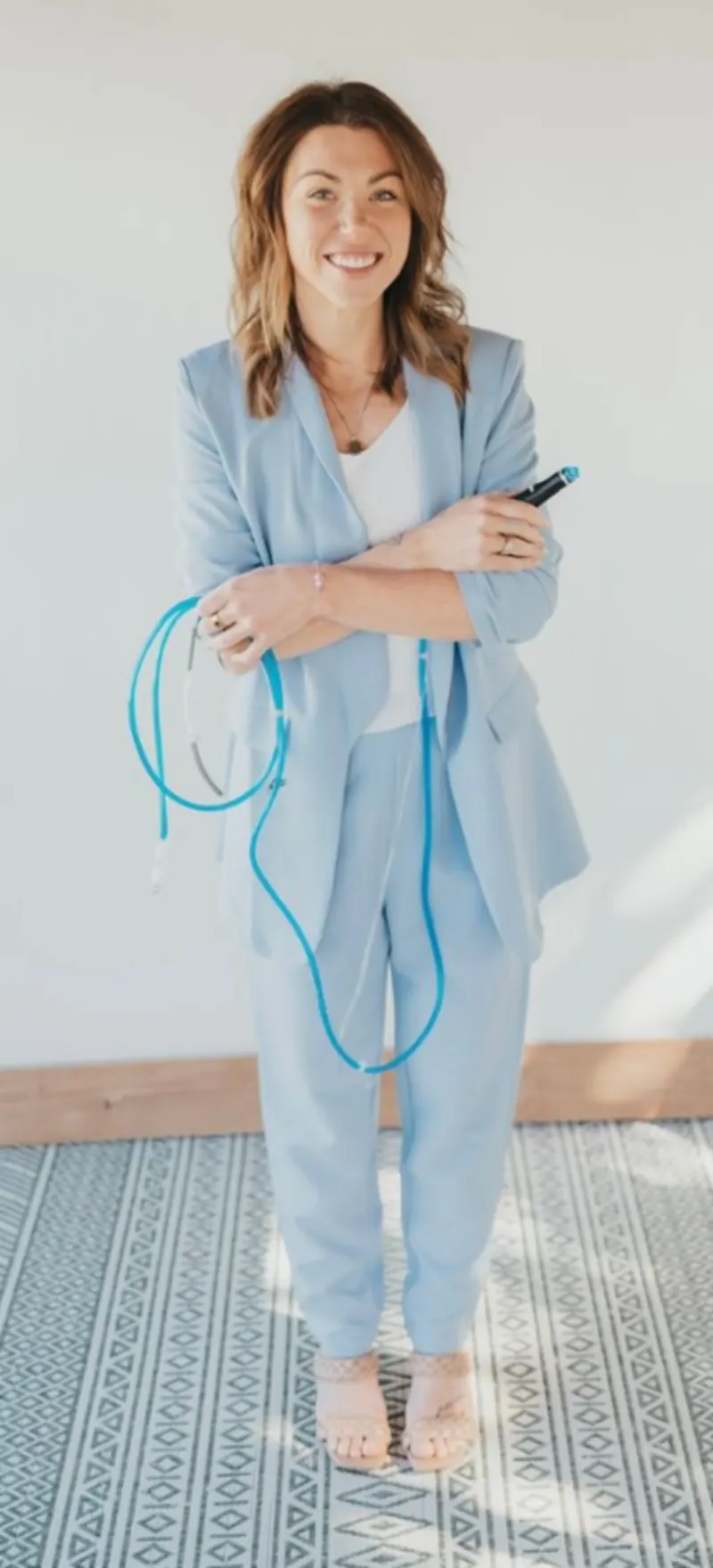 Kate, esthetician and owner of Esthetically Kate Spa, in a light blue suit holding Hydrafacial equipment
